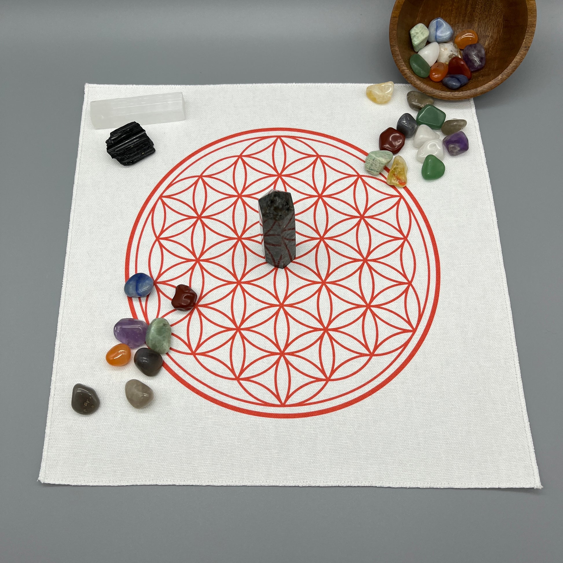 12 Inch Flower of Life Crystal Grid Cloth with Tumbled Crystals and a Crystal Tower Placed on it and complete with Clear Quartz Point, Selenite Wand, and Black Tourmaline Displaying the Grid Cloth in Use.