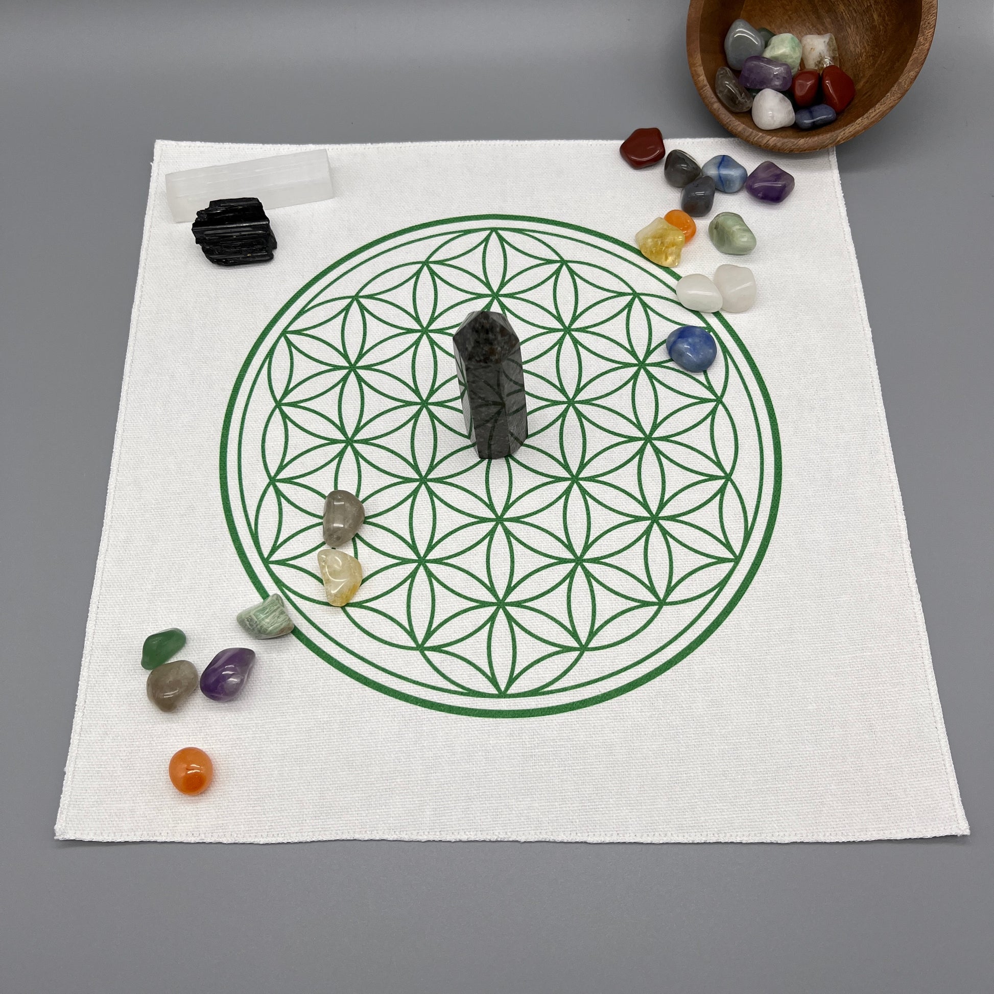 12 Inch Flower of Life Crystal Grid Cloth with Tumbled Crystals and a Crystal Tower Placed on it and complete with Clear Quartz Point, Selenite Wand, and Black Tourmaline Displaying the Grid Cloth in Use.