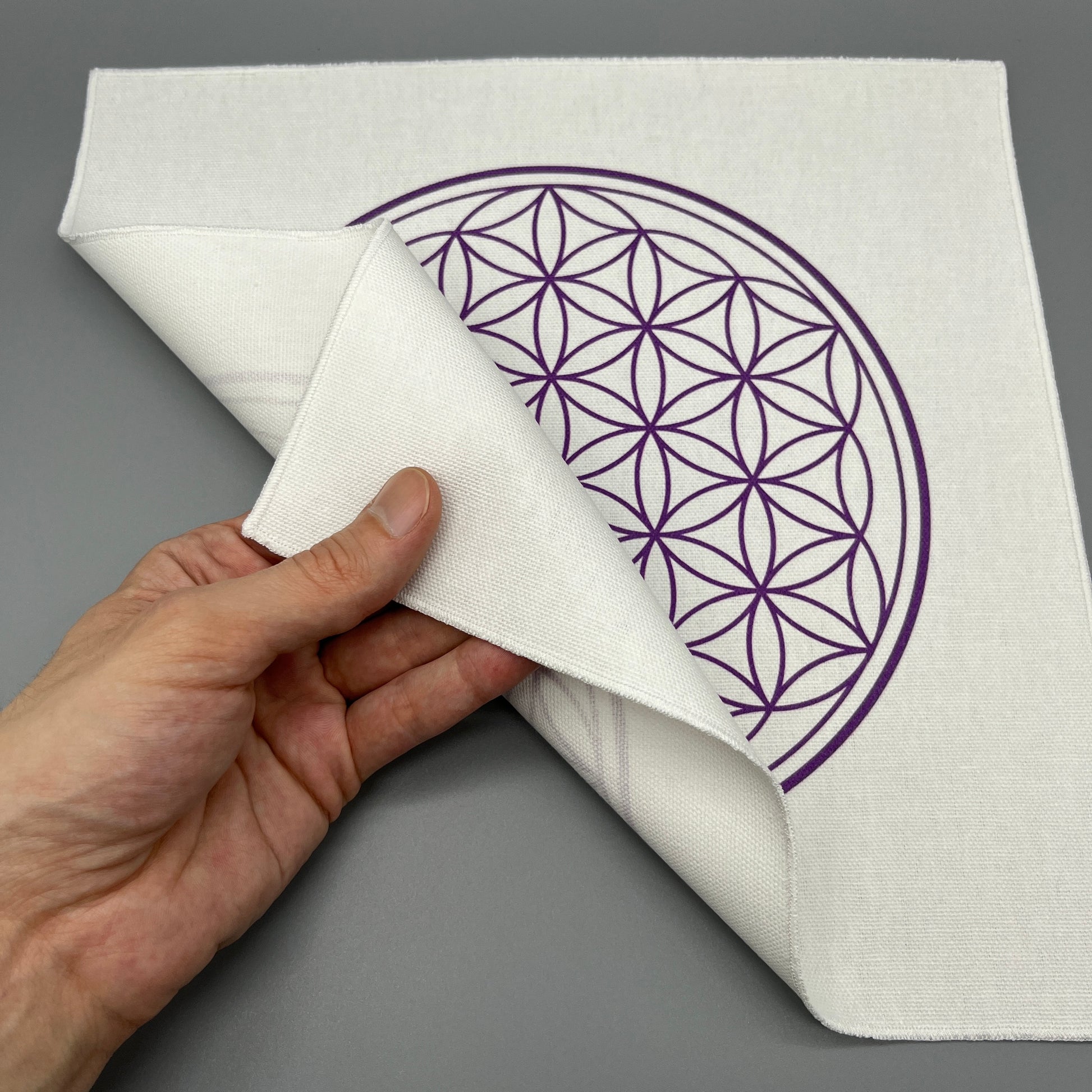 12 Inch Flower of Life Crystal Grid Cloth Being Held Up to Show the Black Back Side and Flower of Life Symbol Showing Through Slightly